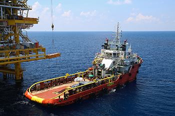 Boat sitting in a large open water next to a crane